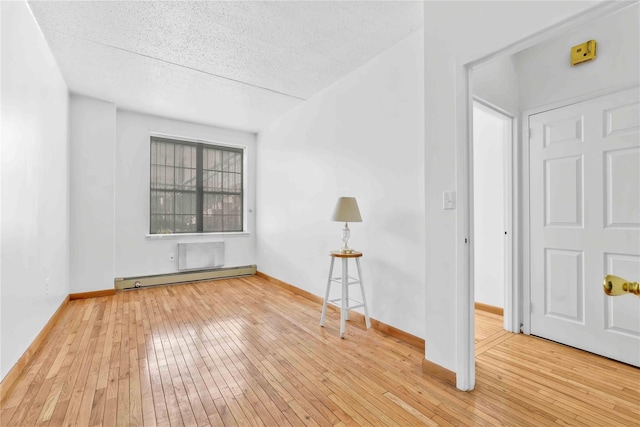 spare room with a textured ceiling, baseboards, wood-type flooring, and a baseboard radiator