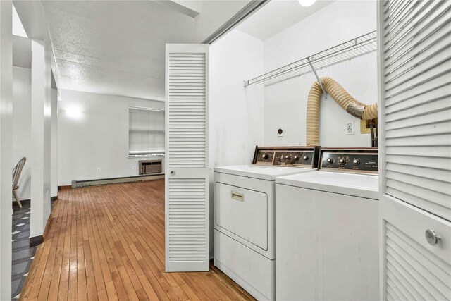 laundry area with laundry area, a baseboard radiator, light wood-style floors, and separate washer and dryer