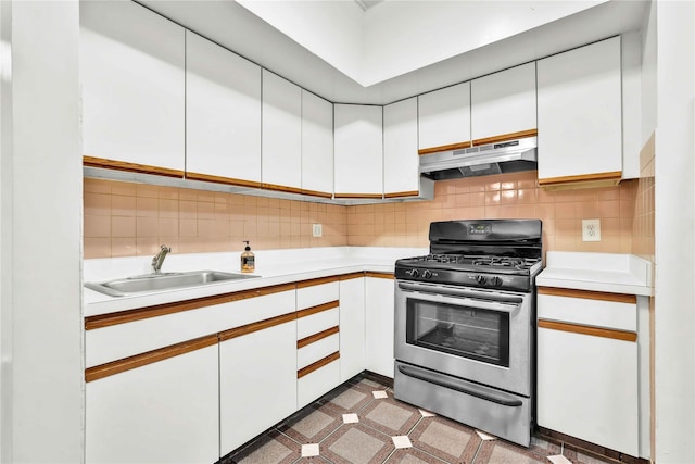 kitchen featuring under cabinet range hood, gas range, light countertops, and a sink