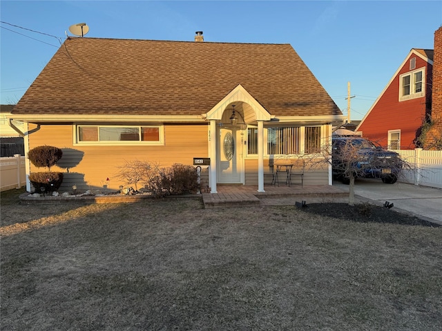 view of front of home with roof with shingles, a chimney, and fence