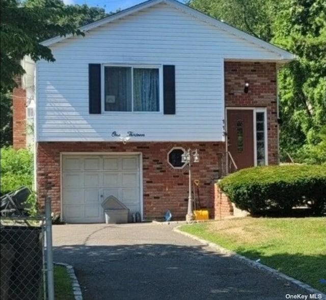 view of front of home featuring aphalt driveway, a garage, and brick siding