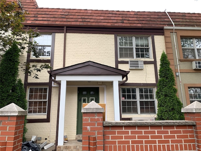 view of exterior entry featuring brick siding and a wall unit AC