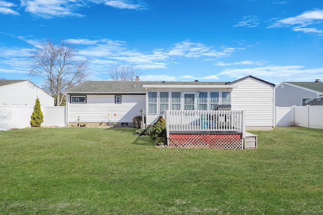 rear view of house with a yard, a fenced backyard, a sunroom, and a wooden deck