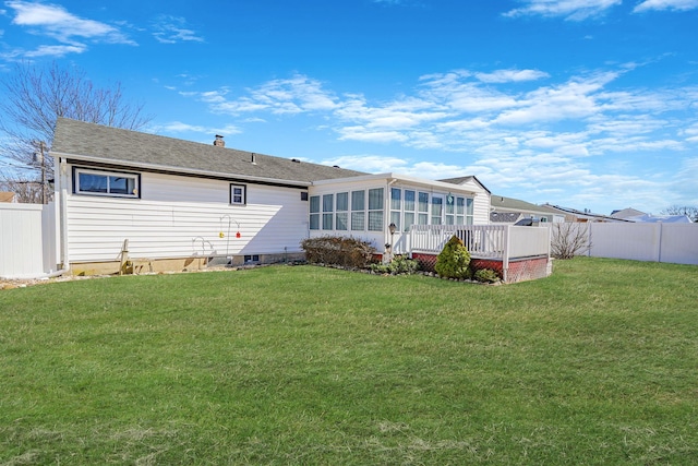 rear view of house with a yard, fence, a chimney, and a sunroom