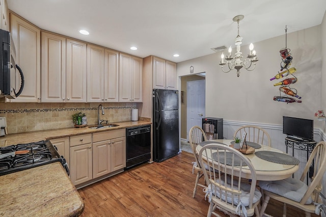 kitchen featuring visible vents, light wood-style flooring, a sink, black appliances, and light countertops