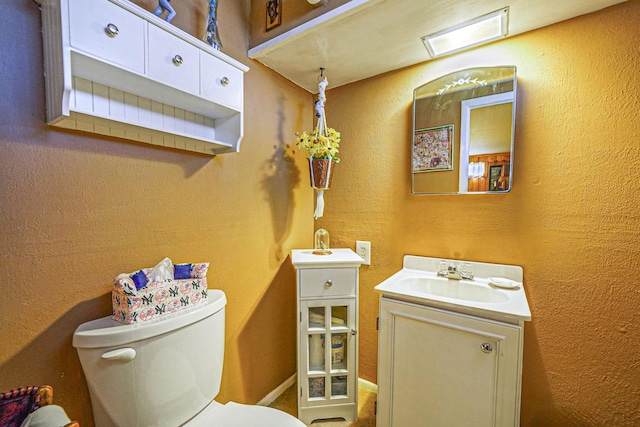 bathroom featuring visible vents, toilet, vanity, and a textured wall