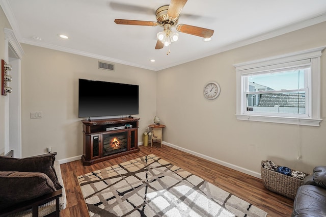 living room with visible vents, baseboards, crown molding, and light wood-style floors