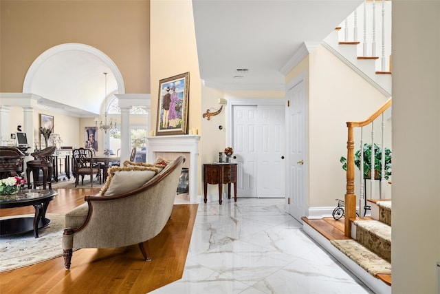 entrance foyer with stairway, decorative columns, arched walkways, and marble finish floor