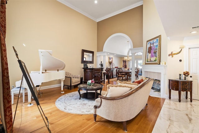 living room featuring baseboards, a fireplace, arched walkways, and ornamental molding