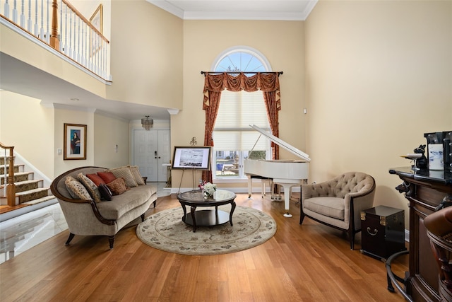 living room featuring stairs, wood finished floors, a wealth of natural light, and ornamental molding