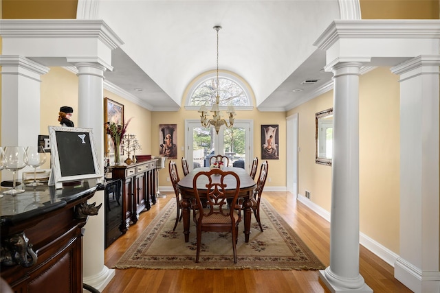 dining area with light wood finished floors, crown molding, and ornate columns