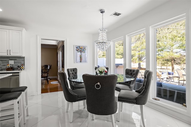 dining room featuring a notable chandelier, light tile patterned flooring, visible vents, and baseboards