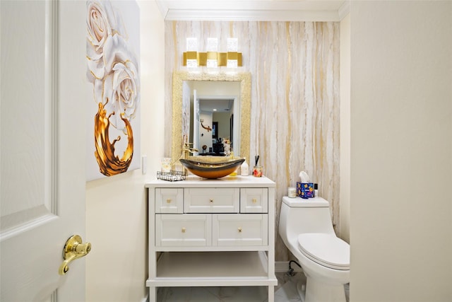 bathroom with toilet, vanity, and ornamental molding