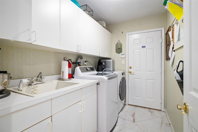 laundry area featuring baseboards, washer and clothes dryer, cabinet space, marble finish floor, and a sink