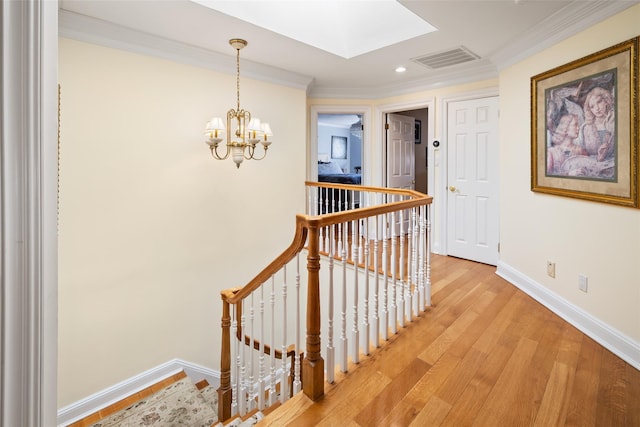 corridor with visible vents, an upstairs landing, light wood-style floors, crown molding, and baseboards