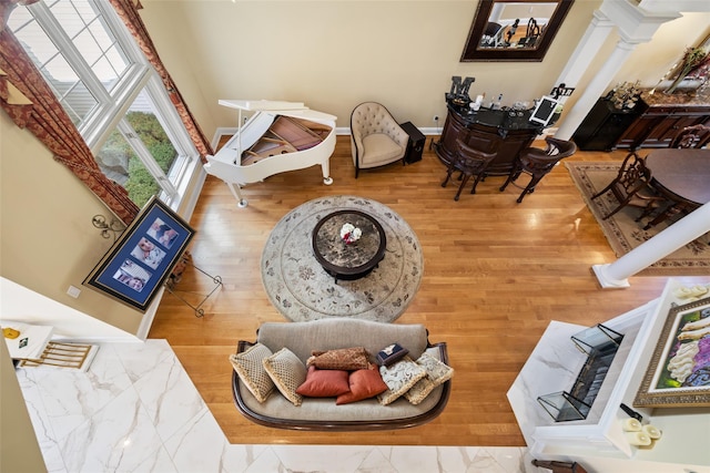 living room featuring baseboards, ornate columns, and wood finished floors