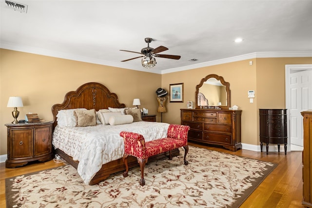 bedroom featuring crown molding, wood finished floors, visible vents, and baseboards