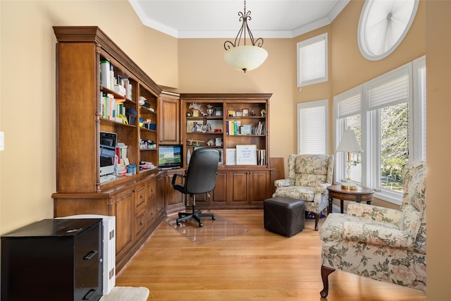 office with ornamental molding, built in desk, a towering ceiling, and light wood-type flooring