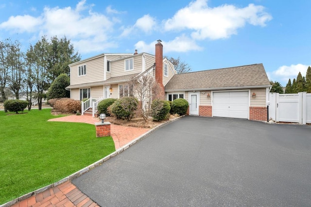 view of front facade with a gate, aphalt driveway, a front yard, a garage, and brick siding