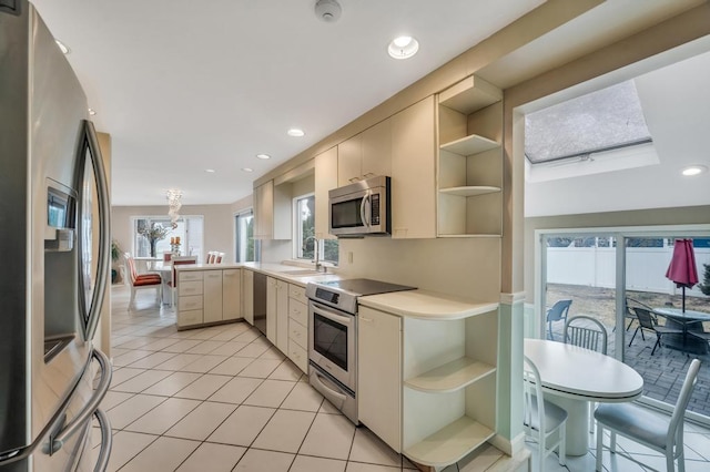 kitchen featuring open shelves, a peninsula, appliances with stainless steel finishes, and a sink