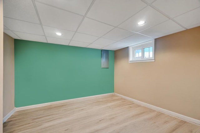 basement featuring wood finished floors, baseboards, and a paneled ceiling