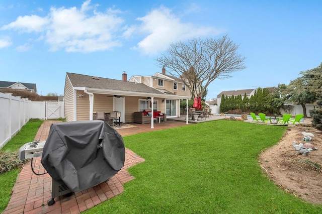 back of house featuring a patio, a gate, a ceiling fan, a yard, and a fenced backyard