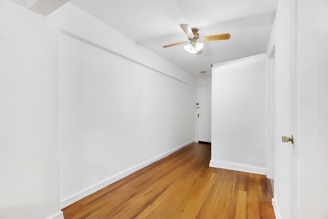 unfurnished room with a ceiling fan, light wood-style floors, and baseboards