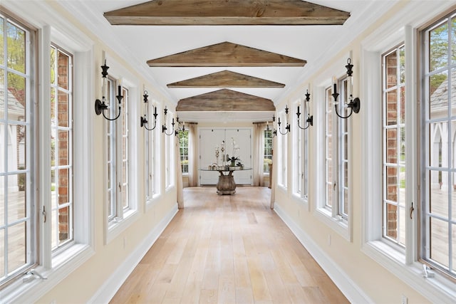 unfurnished sunroom featuring lofted ceiling with beams