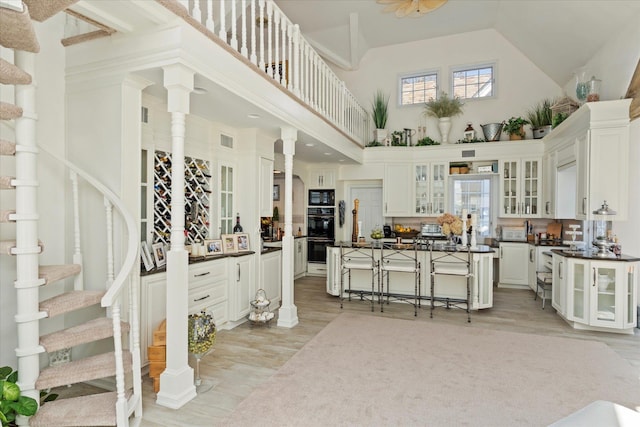 kitchen with dark countertops, black appliances, light wood-type flooring, and a breakfast bar