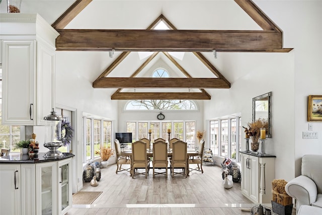 dining space with beamed ceiling, light wood-style flooring, and high vaulted ceiling