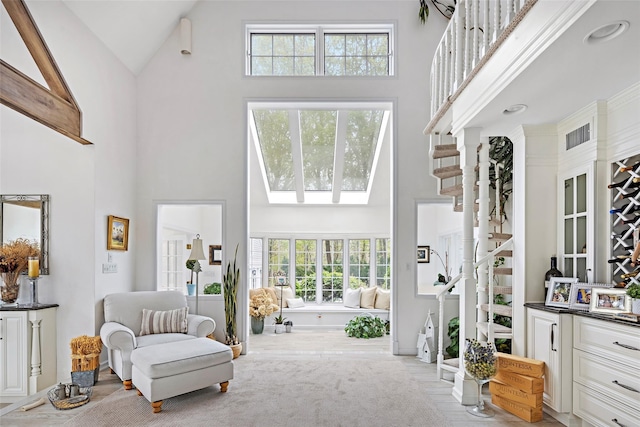 living room with stairway, high vaulted ceiling, and visible vents