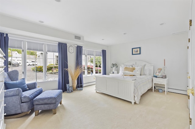 bedroom with a baseboard heating unit, light colored carpet, and visible vents