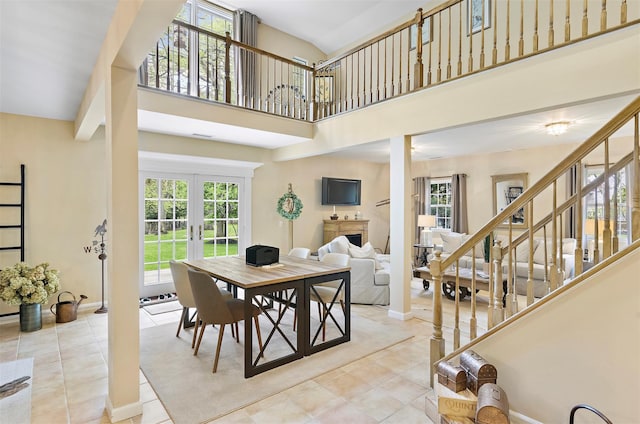 dining area featuring tile patterned flooring, baseboards, stairway, french doors, and a high ceiling