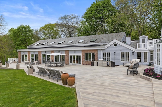 back of house with outdoor lounge area, brick siding, a deck, and a lawn