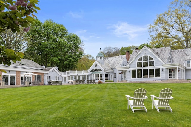 back of house featuring a yard, a chimney, and french doors