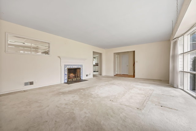 unfurnished living room featuring visible vents, carpet, and a fireplace with flush hearth