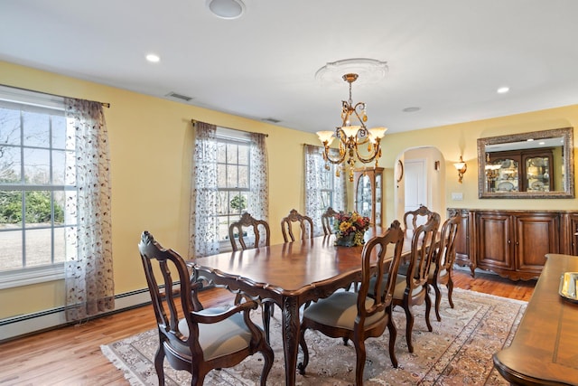 dining room featuring arched walkways, visible vents, light wood finished floors, and a chandelier