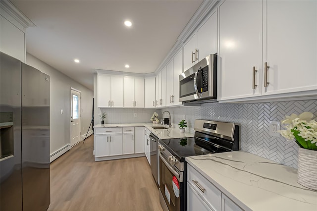 kitchen featuring a baseboard heating unit, light stone counters, appliances with stainless steel finishes, white cabinetry, and a sink