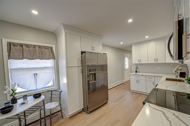 kitchen featuring light stone countertops, a baseboard radiator, white cabinets, appliances with stainless steel finishes, and baseboard heating