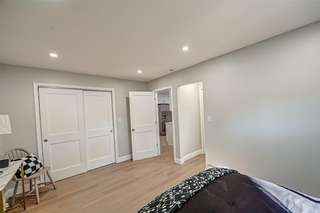 bedroom with a closet, recessed lighting, light wood-style flooring, and stainless steel refrigerator with ice dispenser