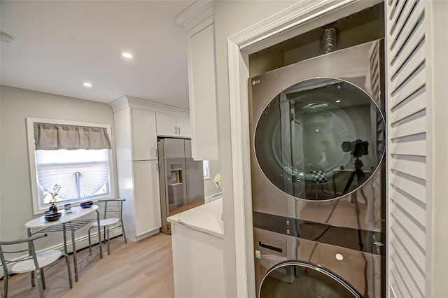 laundry area featuring light wood-type flooring, stacked washer and dryer, laundry area, recessed lighting, and baseboard heating