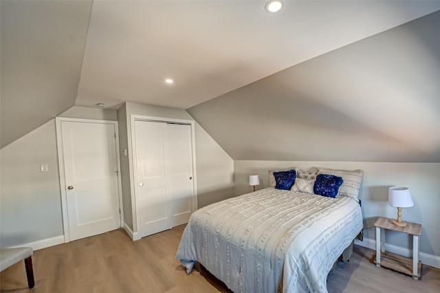 bedroom featuring a closet, baseboards, lofted ceiling, and wood finished floors