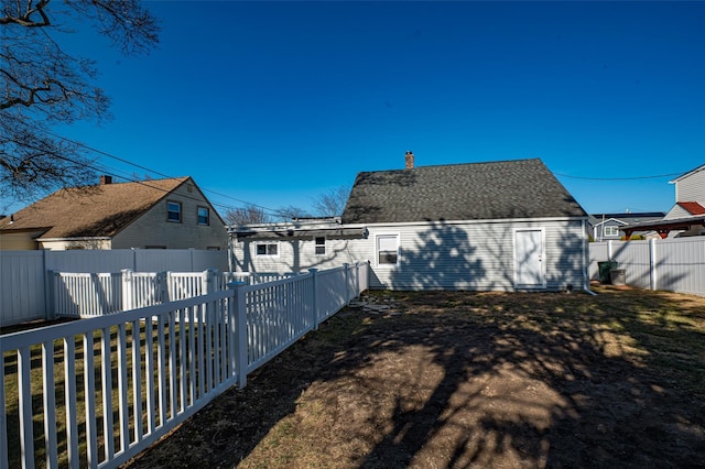 exterior space featuring a fenced backyard, roof with shingles, and a chimney