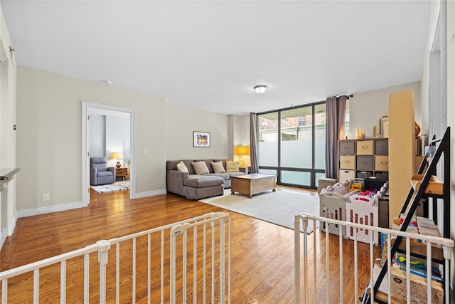 living area with expansive windows, baseboards, and wood finished floors