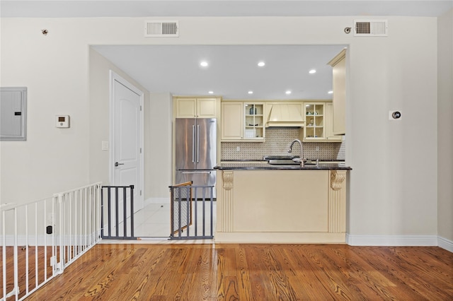 kitchen featuring electric panel, cream cabinetry, freestanding refrigerator, and visible vents