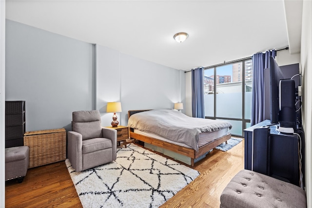 bedroom featuring expansive windows and wood finished floors