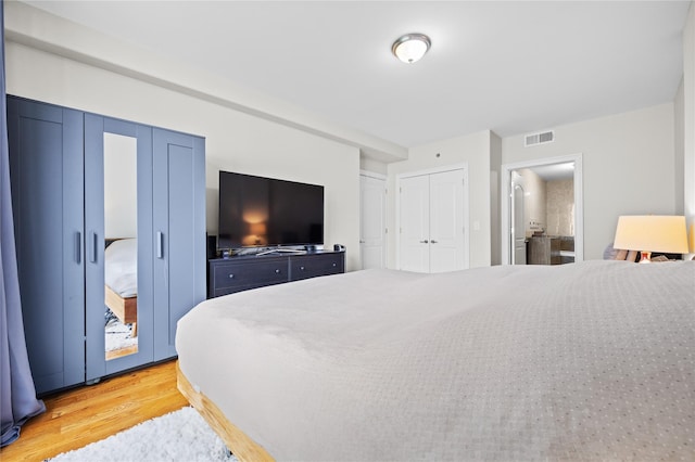 bedroom with two closets, visible vents, and light wood-style floors