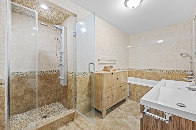 bathroom featuring tile walls, a shower stall, tile patterned flooring, a relaxing tiled tub, and vanity