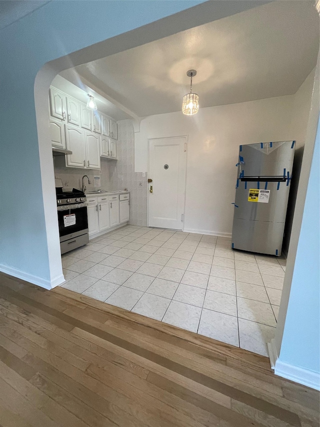 63-60 102nd St Unit B-14, Rego Park, NY 11374 - kitchen featuring appliances with stainless steel finishes, light wood-style floors, arched walkways, white cabinetry, and baseboards