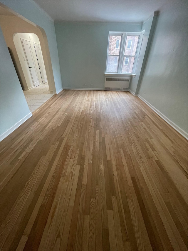 63-60 102nd St Unit B-14, Rego Park, NY 11374 - empty room featuring arched walkways, baseboards, wood finished floors, and radiator